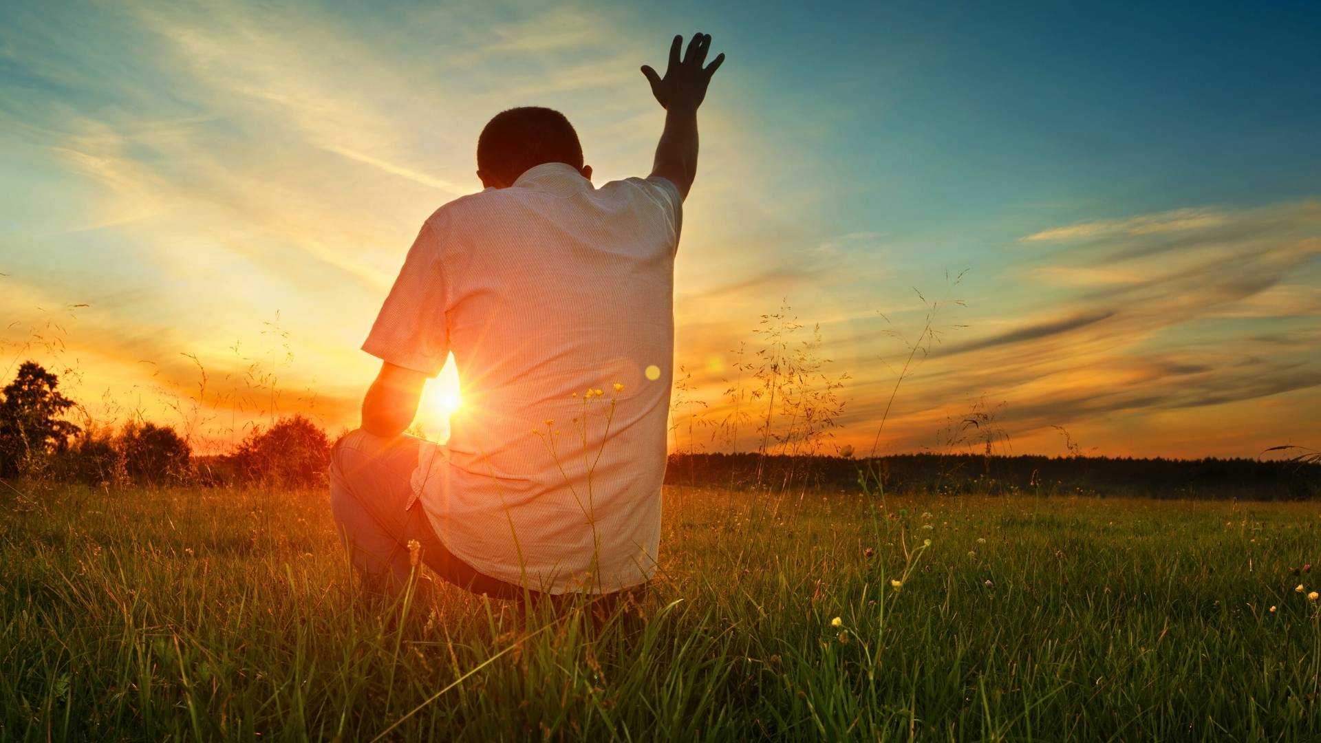 trusting god man kneeling praising god in a field white shirt sunset sky