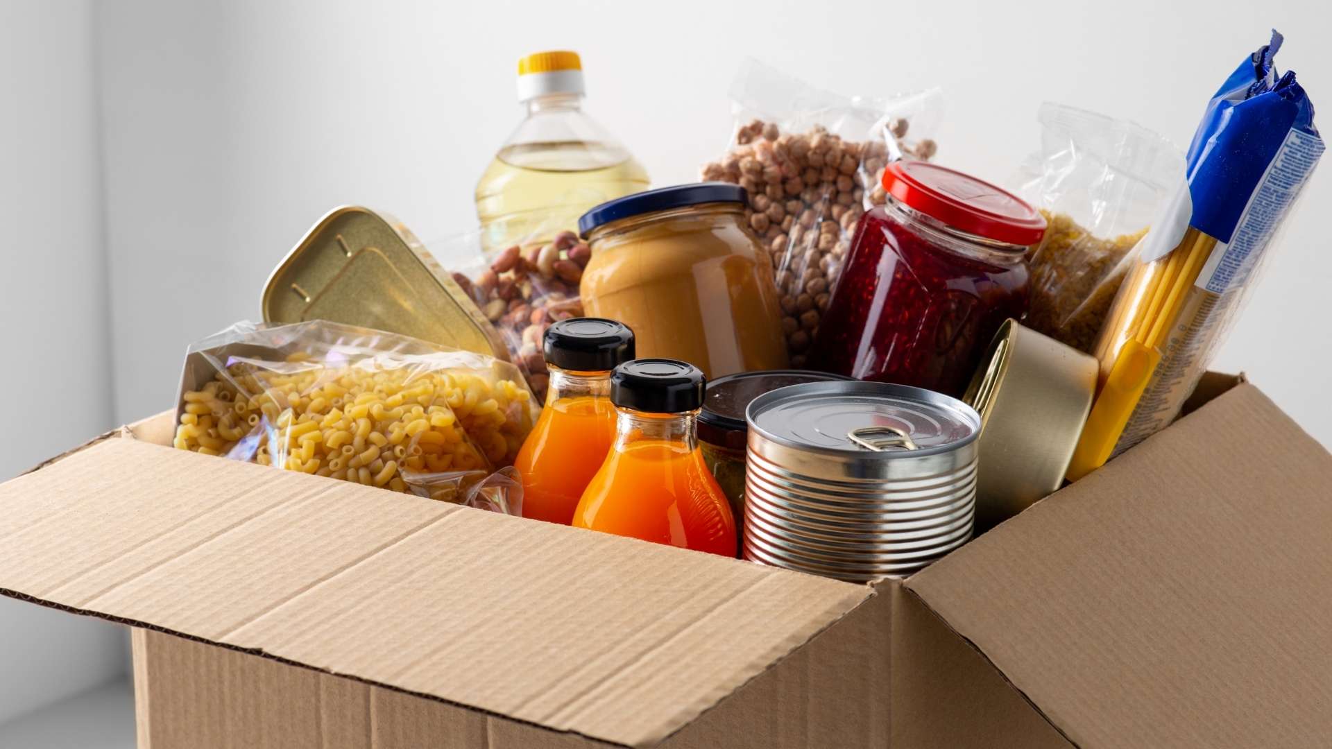 Peanut Butter Jelly cans juices and pasta inside a cardboard box ready to ship