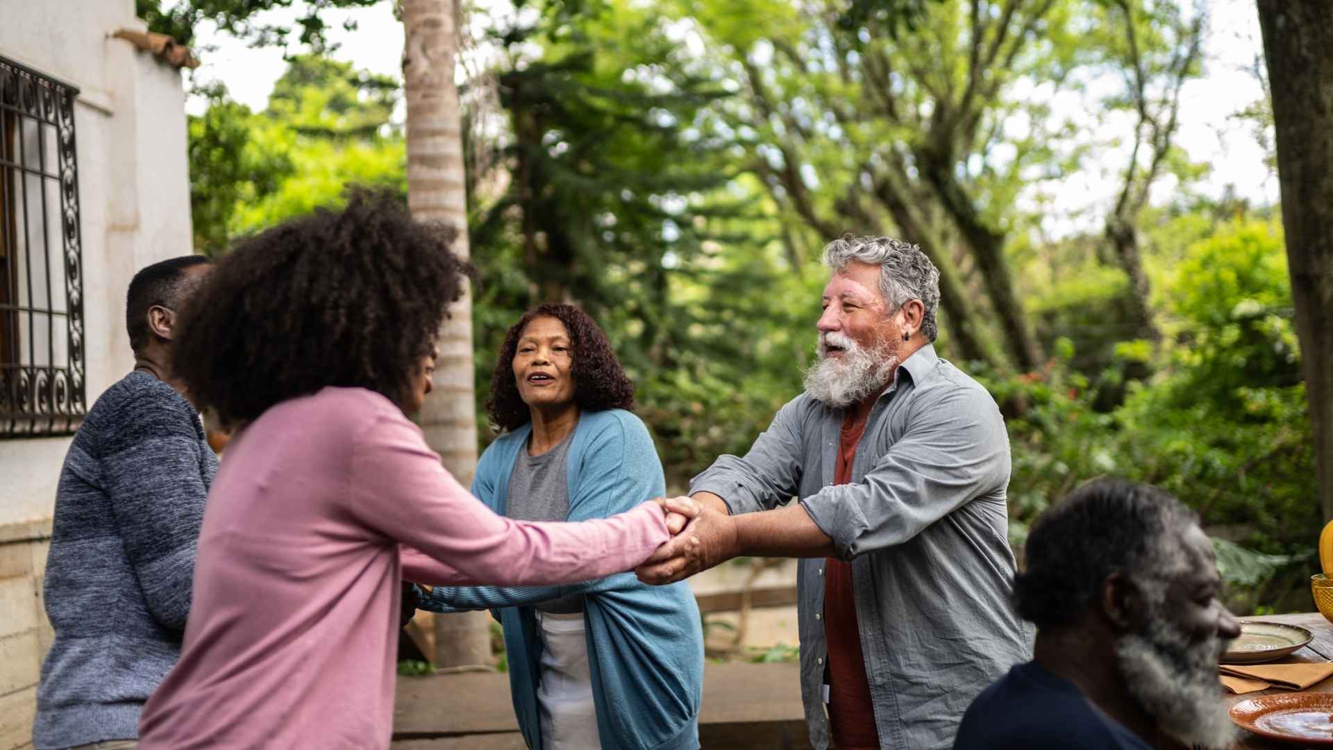 diverse group of people holding arms in a park scene