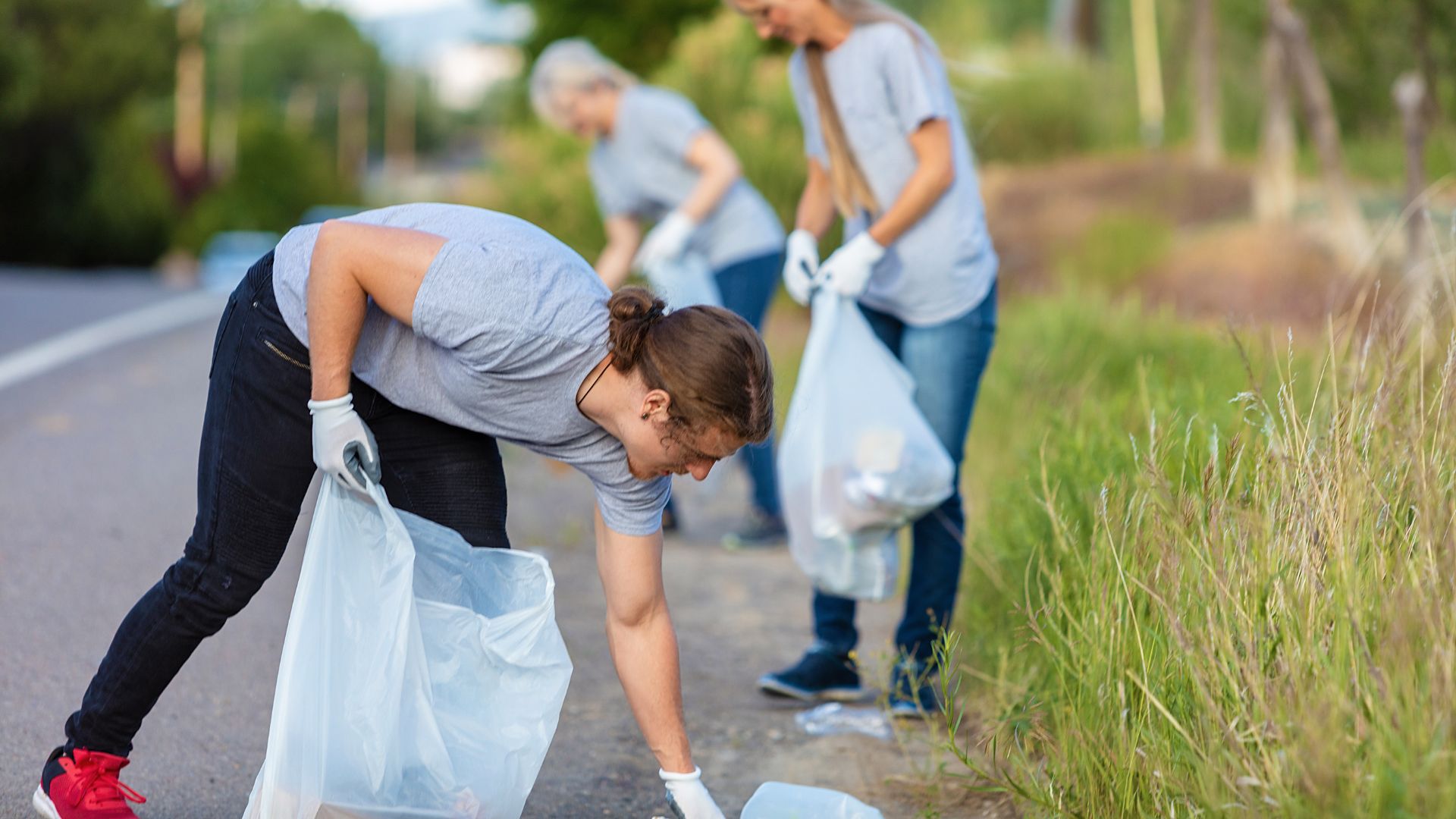 people picking up trash alongside of the road in grassy ditch